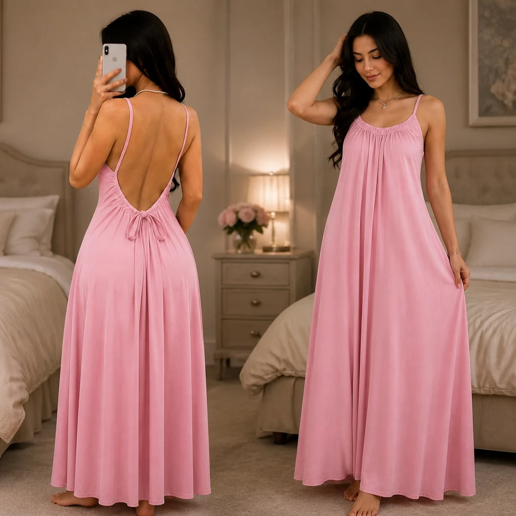 Model wearing a pink backless maxi dress and silky lounge gown by Soft Secrets in a luxury bedroom setting.
