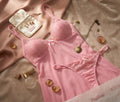 Flat lay of Passione code 3646 pink lace-trim slip nightwear set with Soft Secrets branding, gold mirror, and rose petals.
